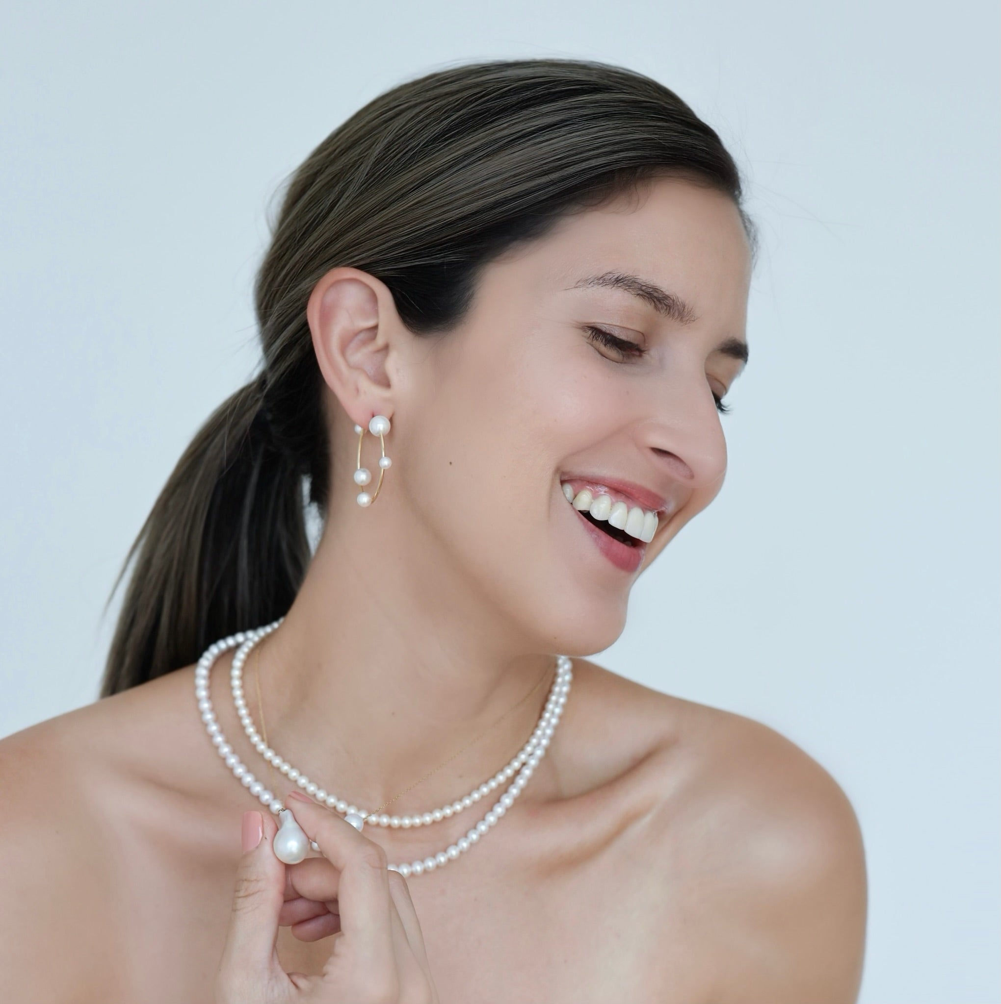 Woman wearing Akoya Hoop Earrings on ear paired with Akoya Baby Pearl Classic Necklace with a Baroque Pearl Charm hooked onto the necklace
