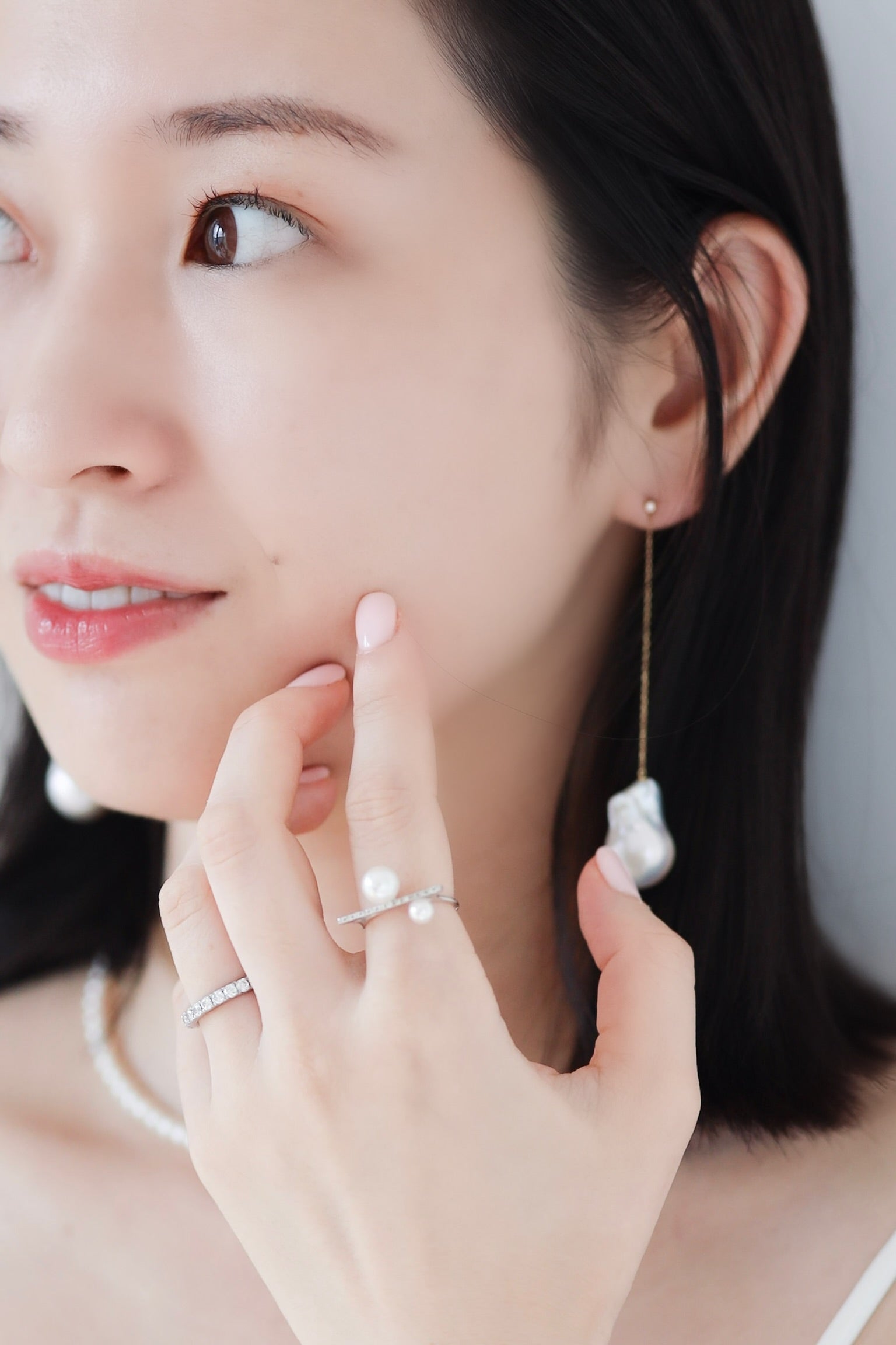 Asian woman wearing Baroque Pearl Swing Earrings with Akoya Diamond Bar Ring on left index finger