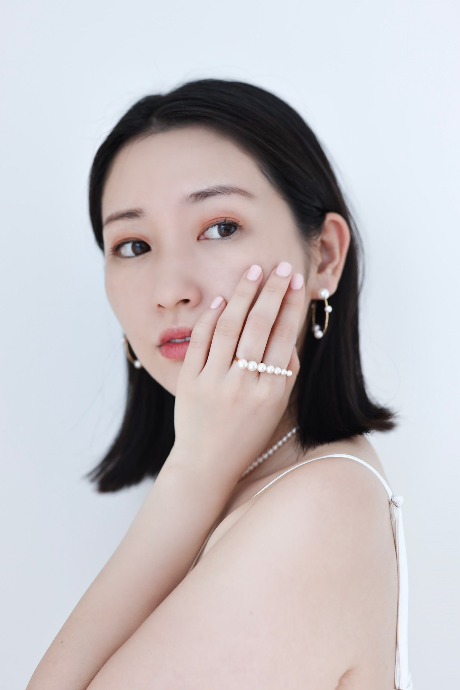 Asian woman wearing Akoya Hoop Earrings paired with Akoya Pearl Double Finger Ring on left hand